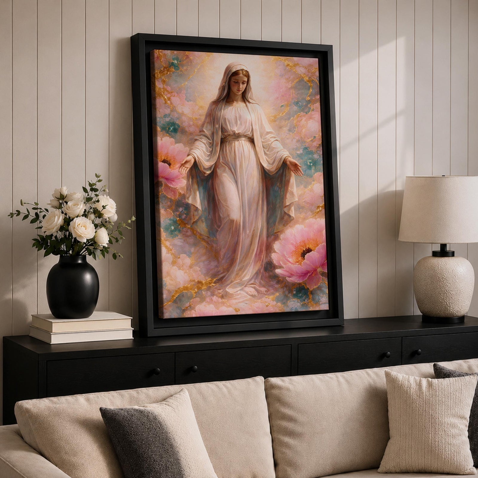 A framed canvas painting depicting the Immaculate Conception showing the Virgin Mary standing with open arms surrounded by soft pink flowers and golden accents, rendered in a realistic style with delicate flowing robes and a serene expression.