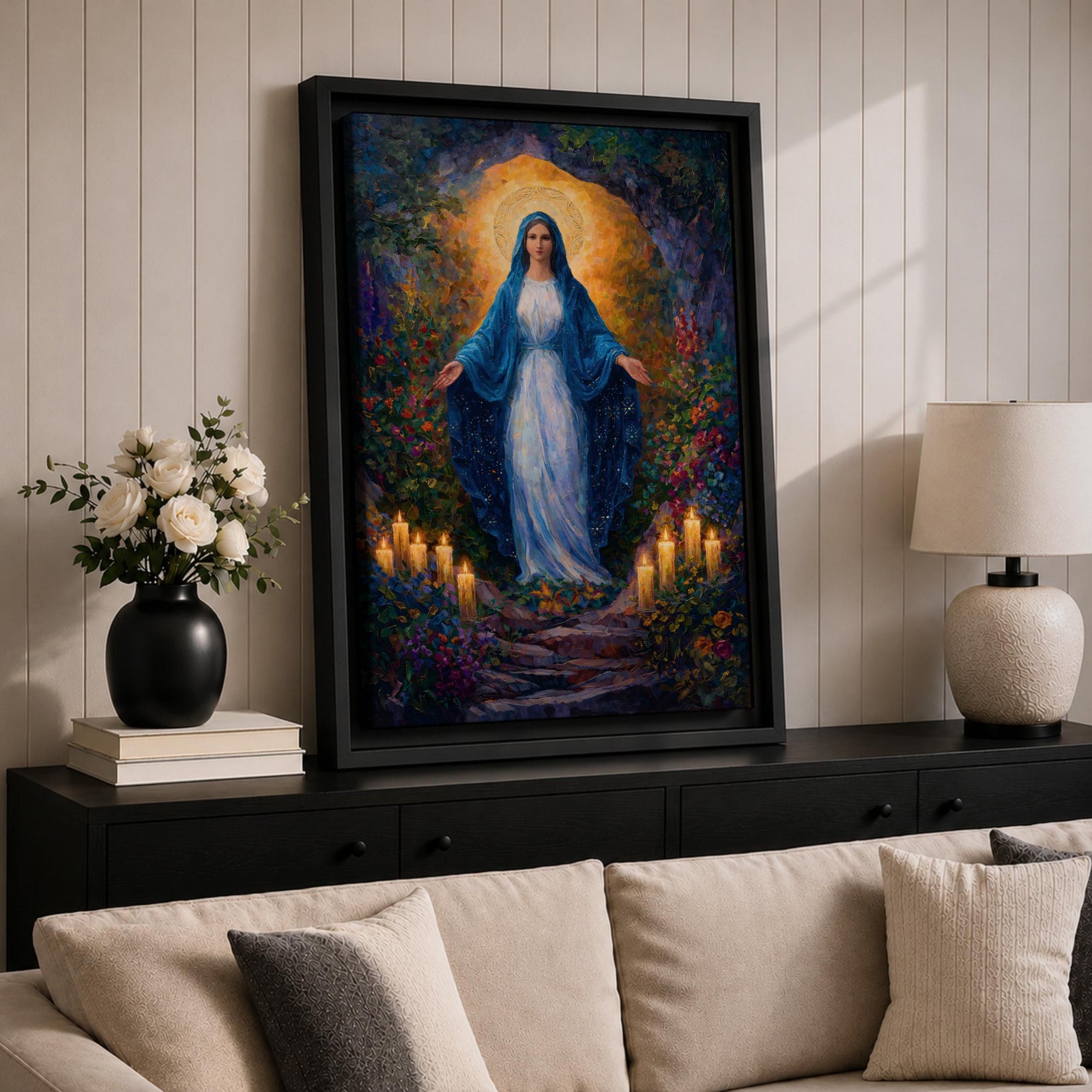 A framed canvas painting of Our Lady of Lourdes depicts the Virgin Mary standing with open arms surrounded by glowing candles and vibrant flowers, rendered in a richly detailed, realistic style with a luminous halo behind her head, evoking a serene and reverent atmosphere.