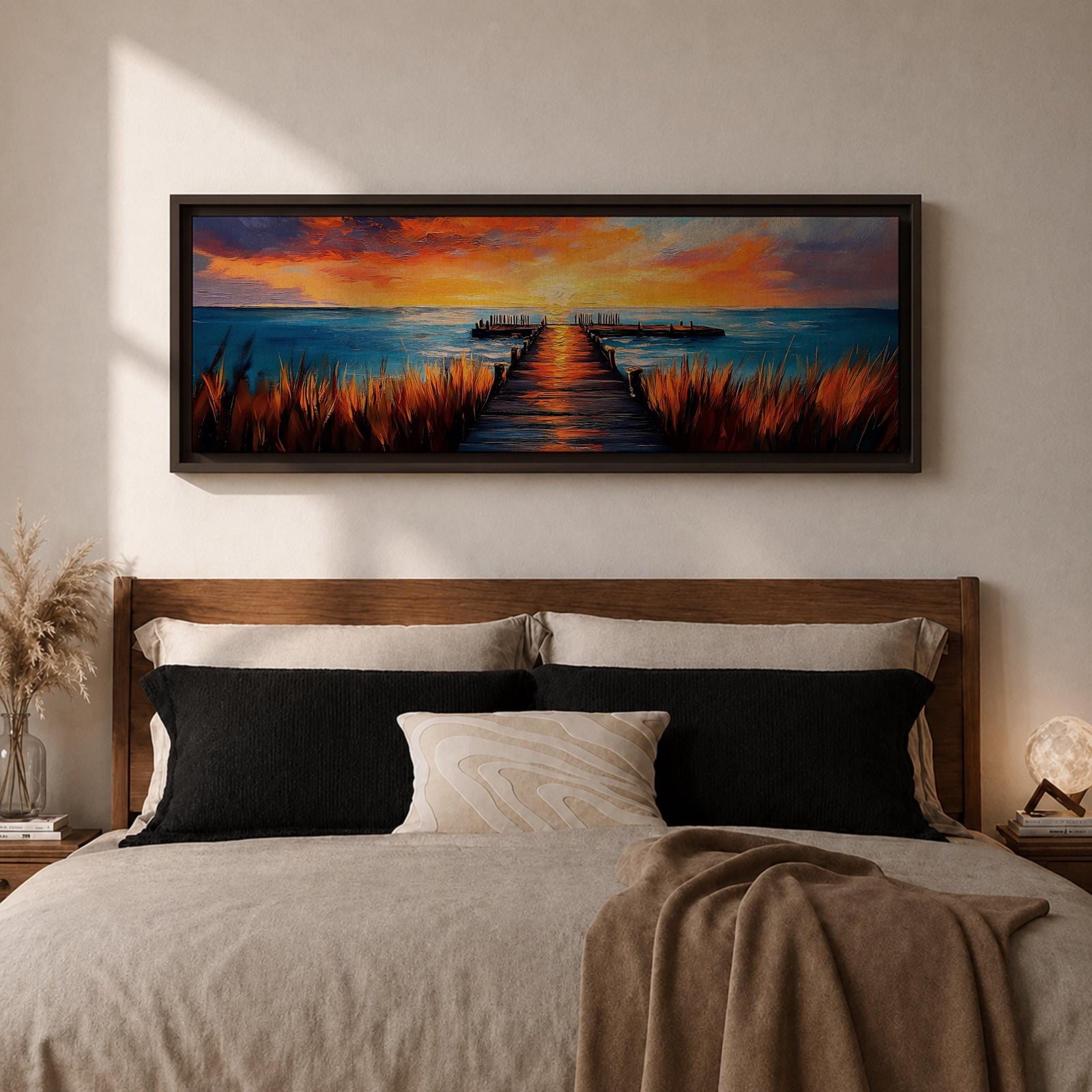 A long narrow panoramic painting depicts a wooden pier extending through tall grasses into calm ocean waters, leading toward a glowing sunset on the horizon, with bold textured brushstrokes and vivid color contrasts capturing reflections of warm light across the water and sky in an expressive contemporary style.