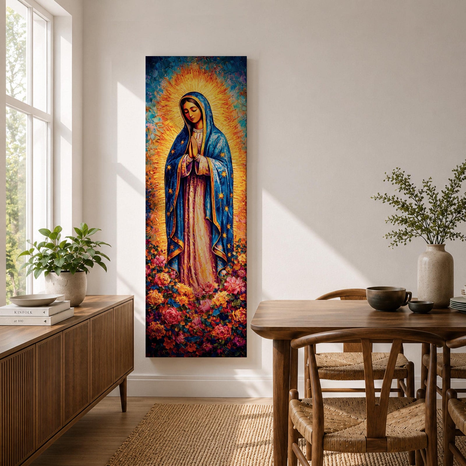 A tall narrow vertical depiction of Our Lady of Guadalupe standing in prayer with hands clasped, wearing a blue star covered mantle and soft pink gown, surrounded by a radiant golden sunburst and dense vibrant floral arrangement at her feet, rendered with rich texture and layered color in a devotional composition.