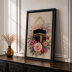 Elegant Kaaba wall art featuring the Holy Kaaba surrounded by blooming pink, blush, purple, and ivory flowers with delicate Islamic arch details. Soft watercolor tones and gold accents create a beautiful Islamic canvas artwork perfect for prayer rooms, bedrooms, and Muslim home decor.